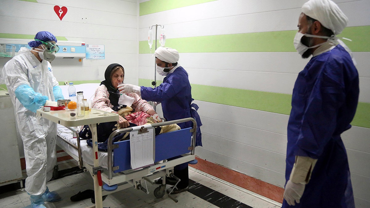 FILE — In this Saturday, March 7, 2020 file photo, a cleric, right, assists a medic treating a patient infected with the new coronavirus, at a hospital in Qom, about 80 miles (125 kilometers) south of the capital Tehran, Iran. Nine out of 10 cases of the virus in the Middle East come from the Islamic Republic. (Mohammad Ali Marizad/Rasa News Agency via AP, File)