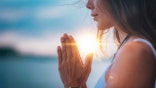 Young woman meditating with her eyes closed, practicing Yoga with hands in prayer position.