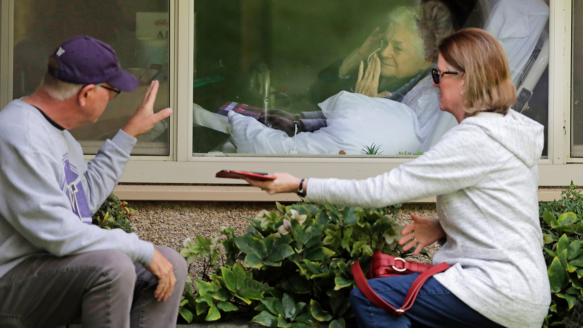 Judie Shape who has tested positive for the coronavirus blows a kiss to her son-in-law, Michael Spencer, and daughter Lori Spencer through a hospital window in Kirkland, Washington, March 11, 2020. 