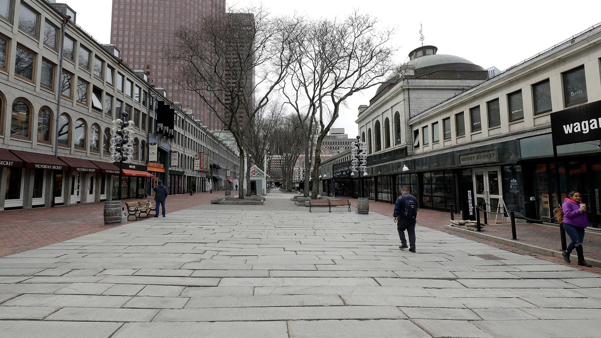 People walk through the nearly empty tourist area of Quincy Market in Boston, Mar. 11, 2020.