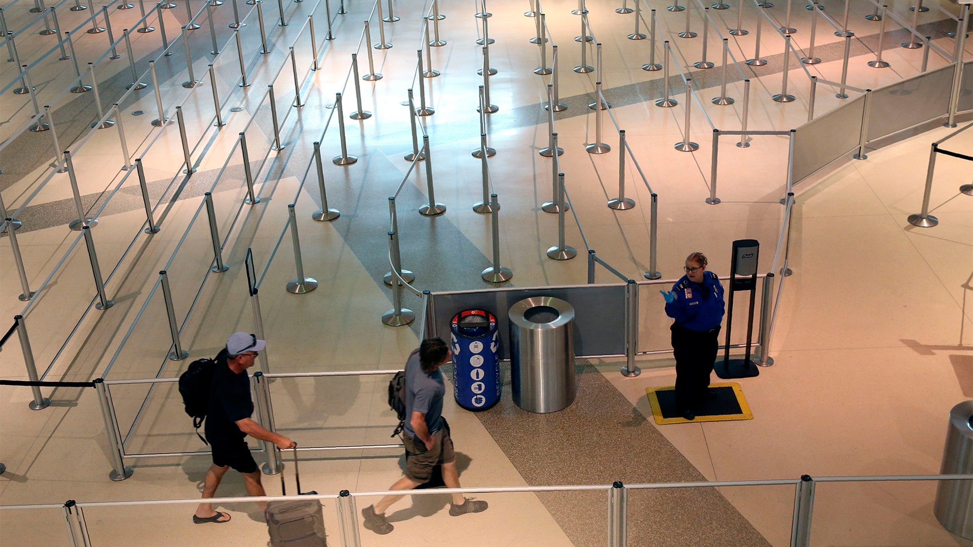 A TSA agent speaks to travelers passing through an empty security queue at Love Field airport amid concerns of the coronavirus pandemic in Dallas, Mar. 12, 2020.