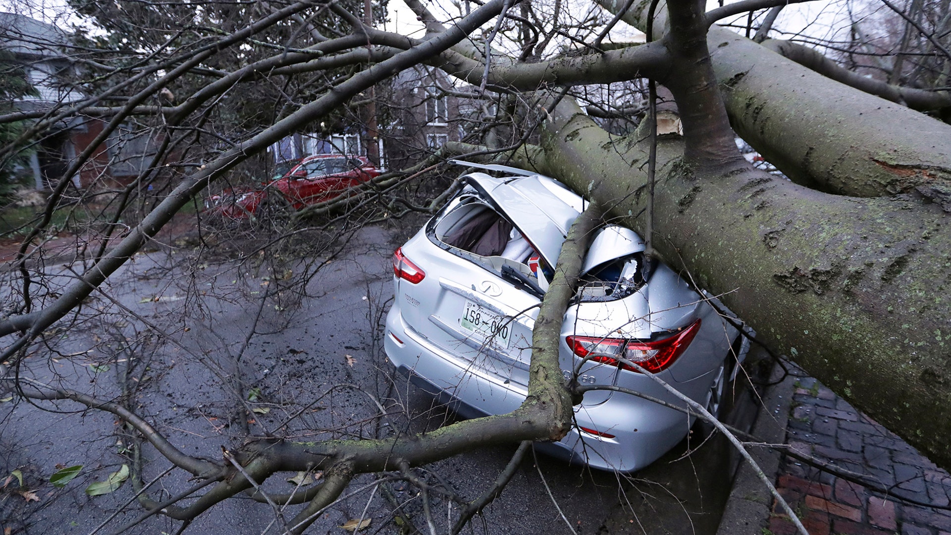 A car crushed by a tree sits on a street after a tornado touched down in Nashville on Tuesday, March 3, 2020.