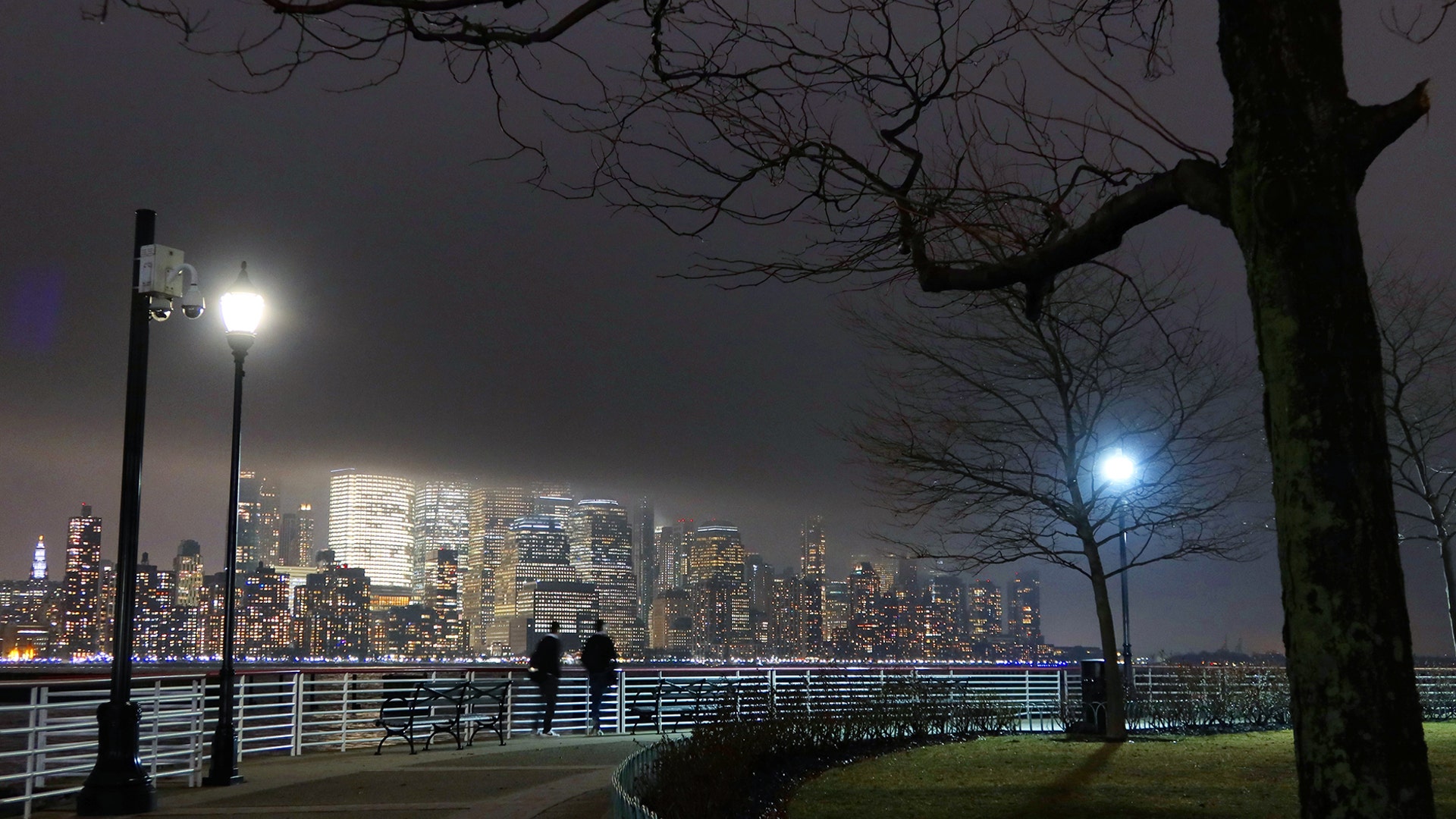 People walk along the Hudson River as fog shrouds lower Manhattan in New York City, March 4, 2020.