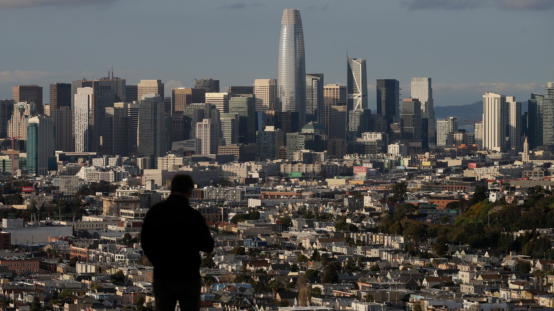 A man stands in front of the skyline from Bernal Heights Hill in San Francisco, March 16, 2020. 