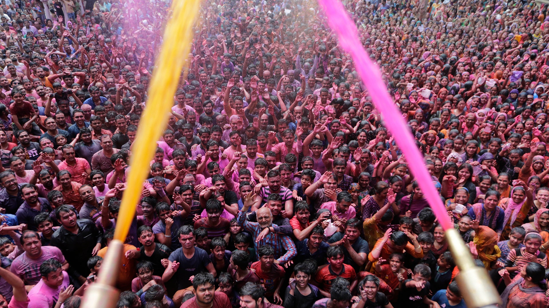 Indian Hindu devotees cheer as colored powder and water is sprayed on them by a Hindu priest during celebrations marking Holi at the Swaminarayan temple in Ahmedabad, India, March 10, 2020.