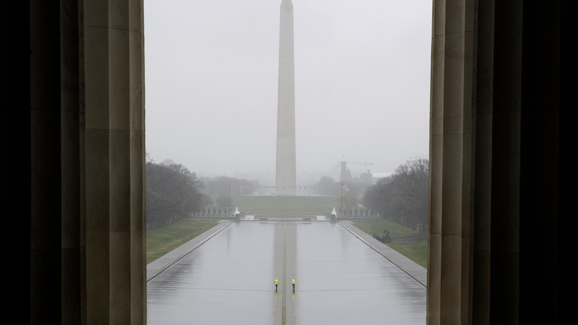 People walk in an empty Lincoln Memorial Reflecting Pool in Washington, D.C., March 25, 2020. 