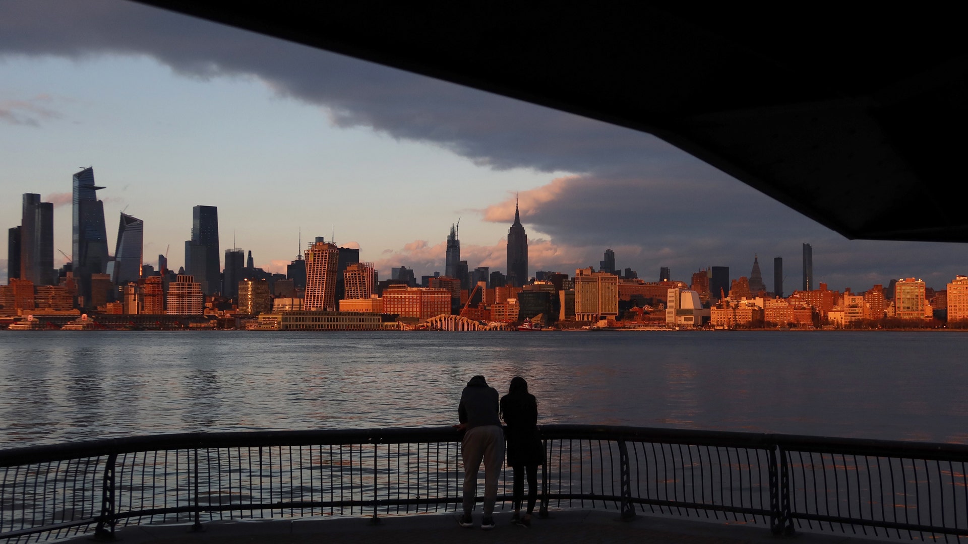 People watch the sun set on midtown Manhattan in New York City from Pier A in Hoboken, N.J., March 17, 2020.