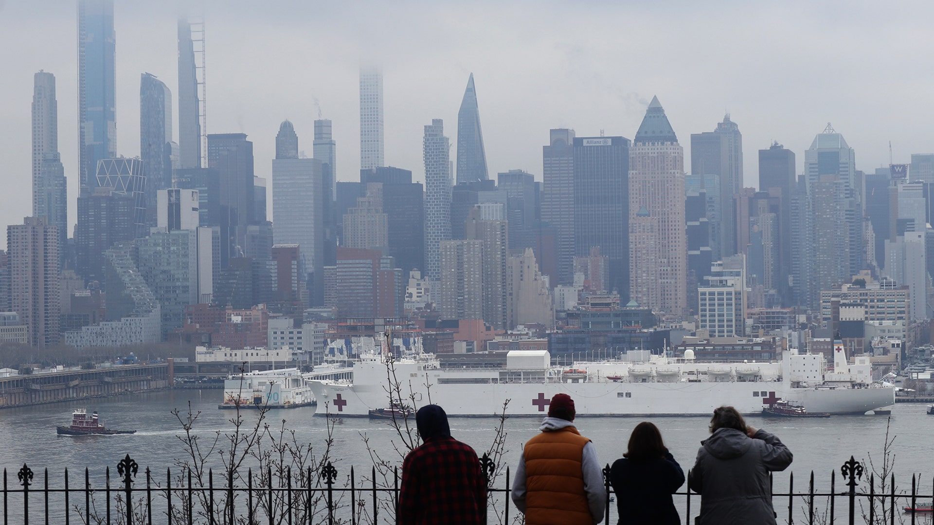 People watch as the USNS Comfort arrives in its port on the Hudson River in New York City, March 30, 2020