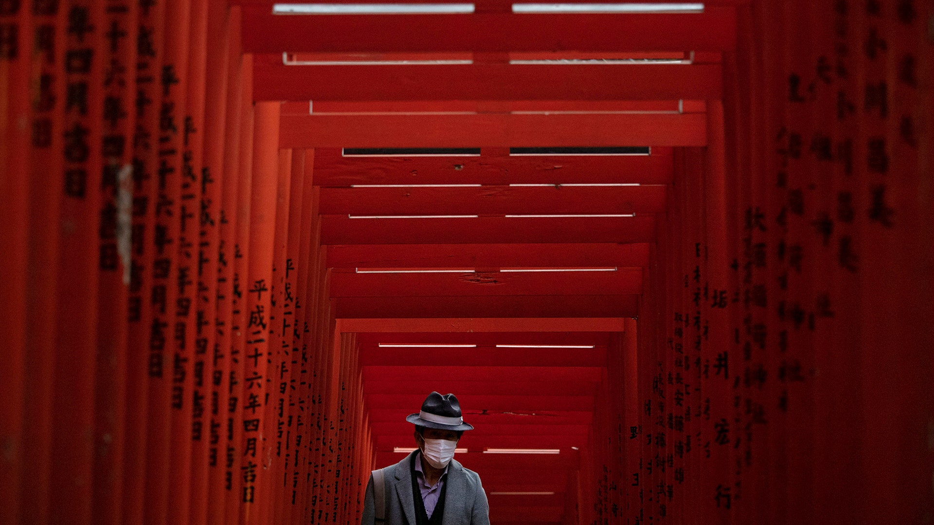 A man with a mask walks through Torii Gates at the Hie Shrine in Tokyo, Japan, March 1, 2020. 
