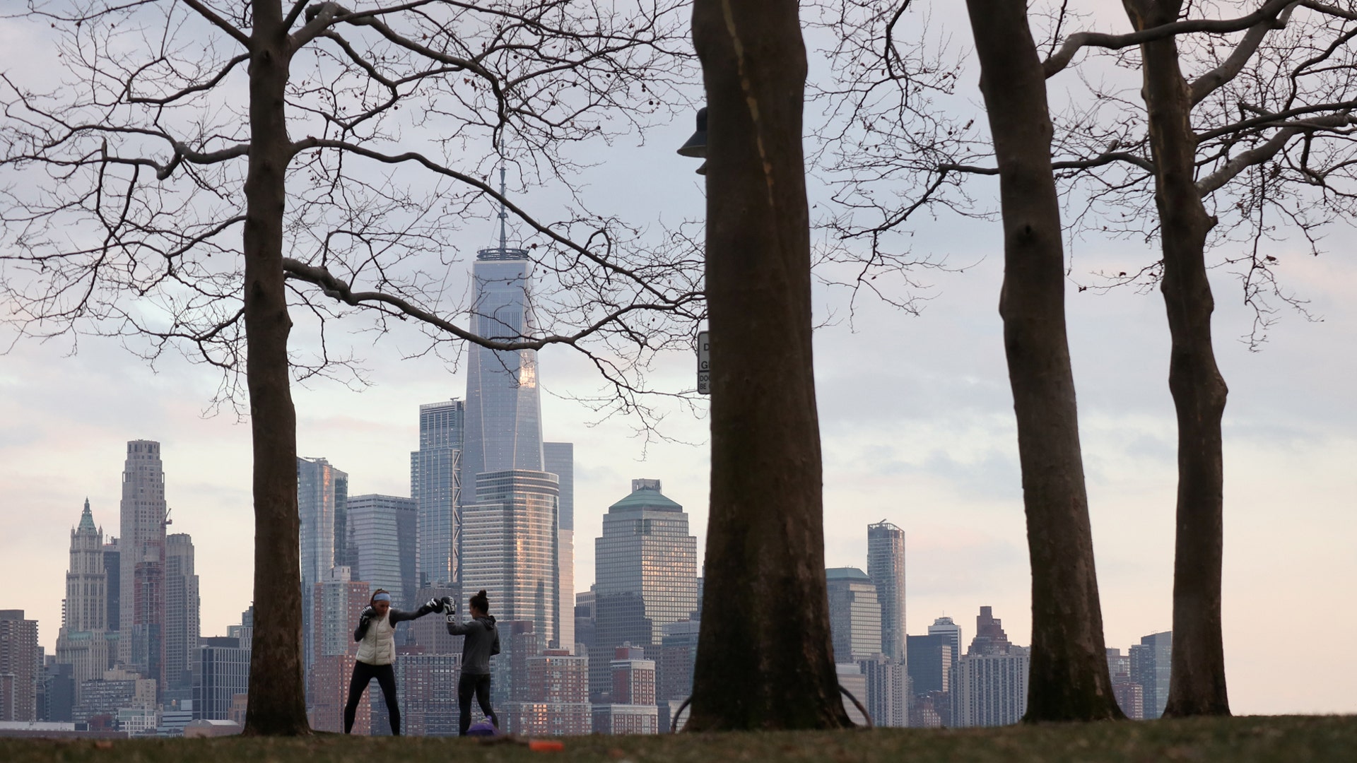 People work out in front of the skyline of lower Manhattan in New York City on Pier A in Hoboken, N.J., March 17, 2020. 