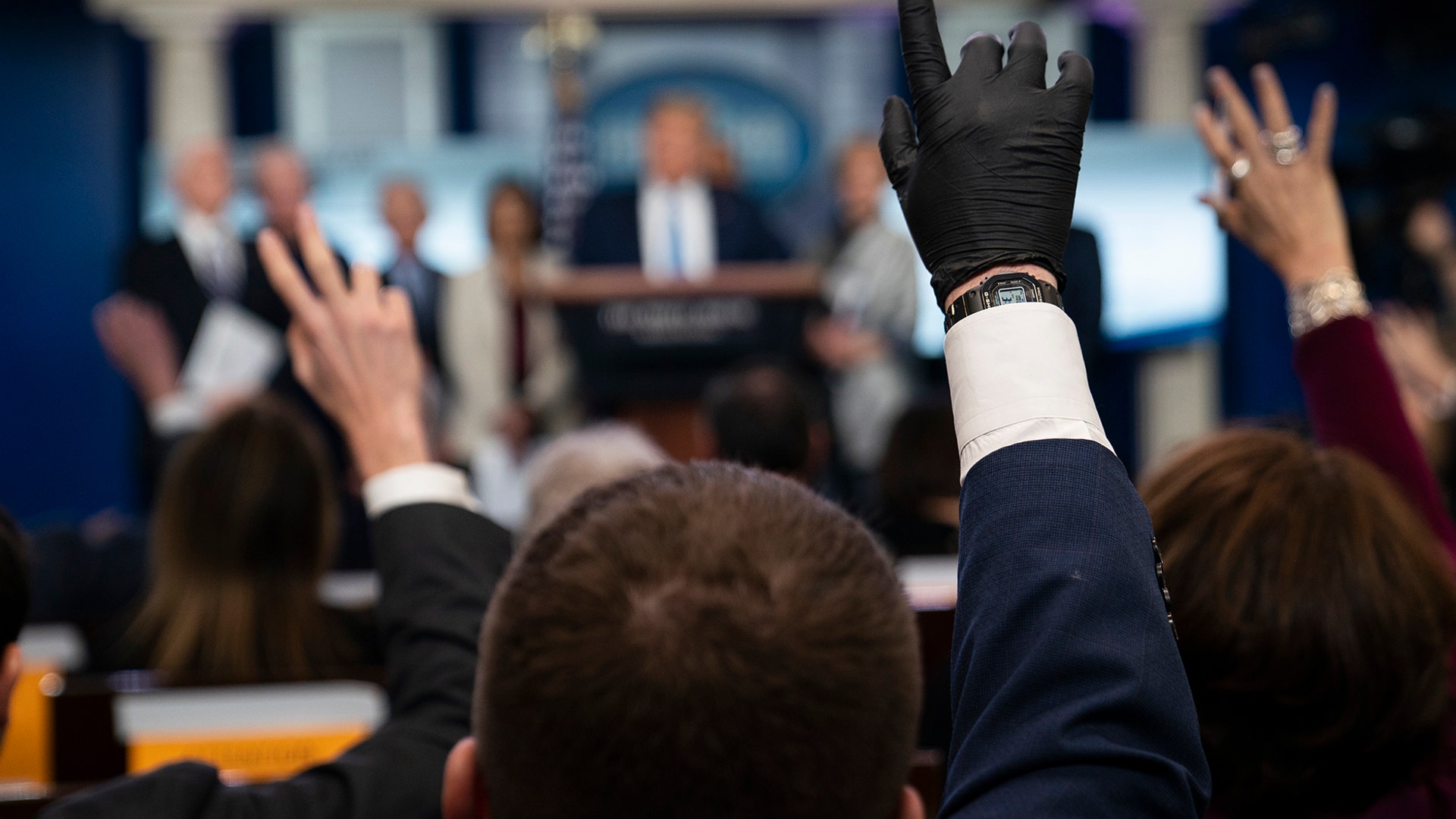 Reporters raise their hands to ask President Donald Trump questions during a press briefing with the coronavirus task force, at the White House, in Washington, March 16, 2020. 