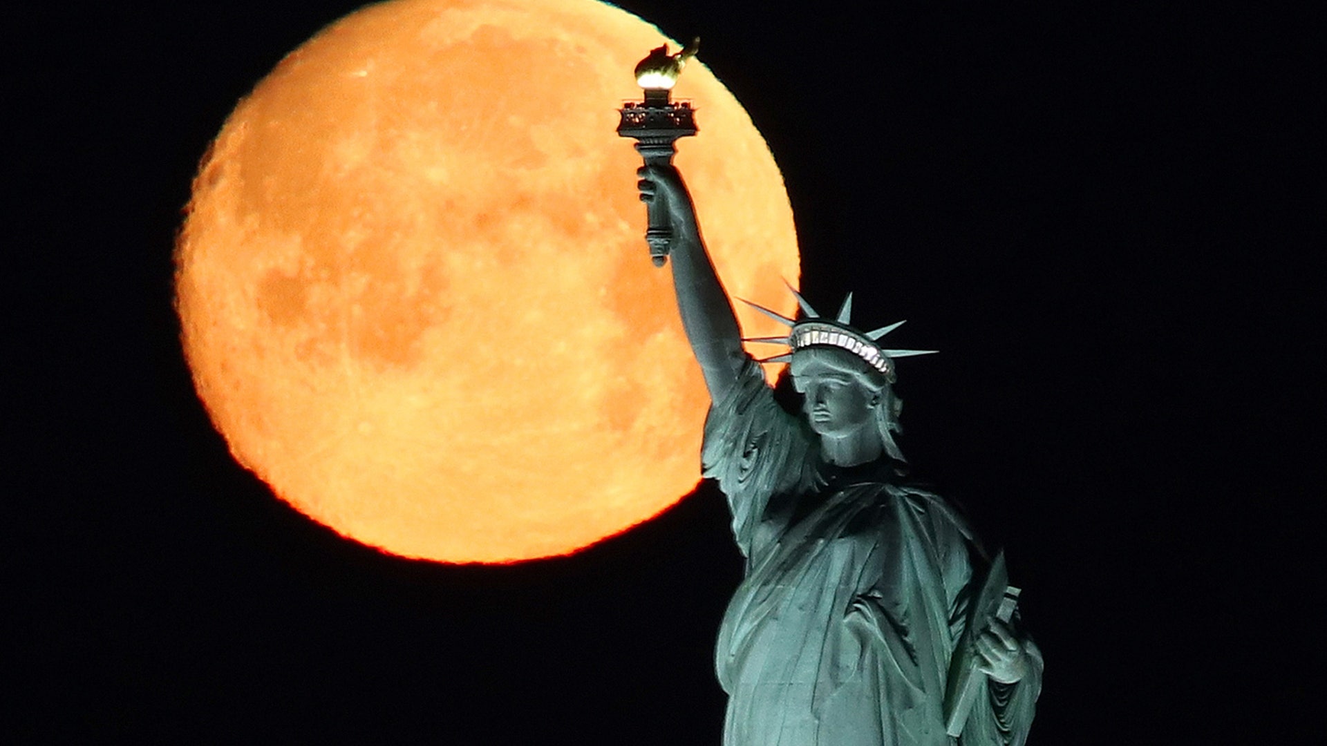 The Super Worm Moon sets behind the Statue of Liberty in New York City, March 9, 2020. 