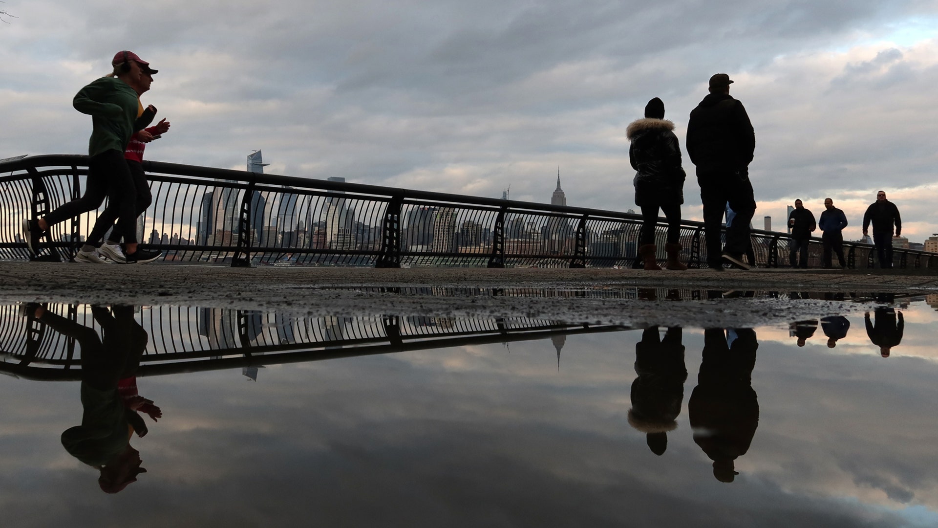 People walk and jog along the Hudson River in Hoboken, N.J., March 17, 2020.