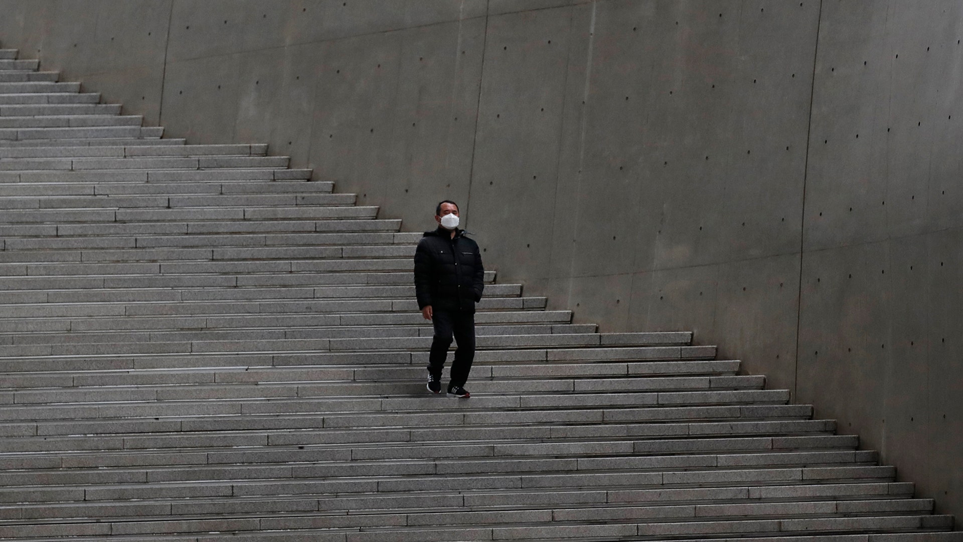 A man wearing a face mask walks down the stairs at Dongdaemun Design Plaza in Seoul, South Korea, March 19, 2020. 