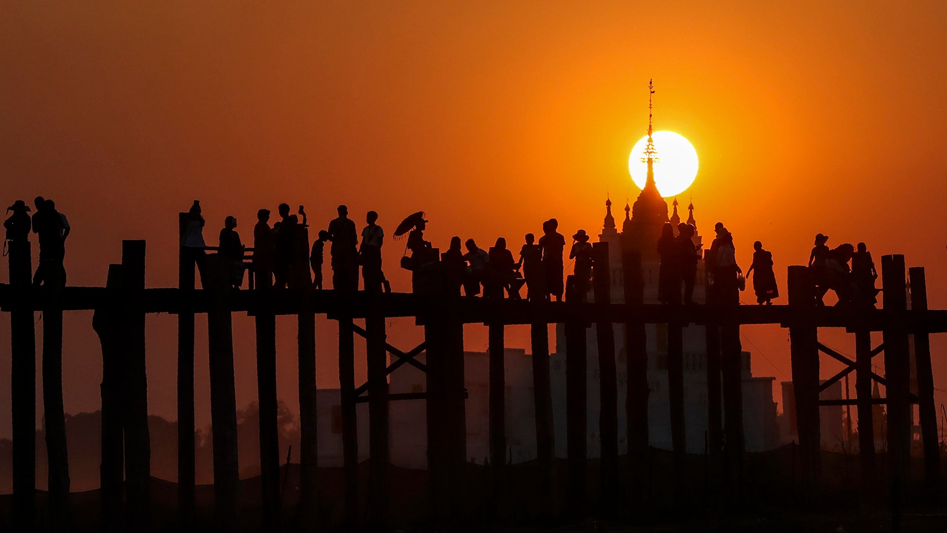 Visitors walk along the long wooden U Bein Bridge that connects the two banks of Taungthaman Lake as the sun sets in Mandalay, Myanmar, March 11, 2020.