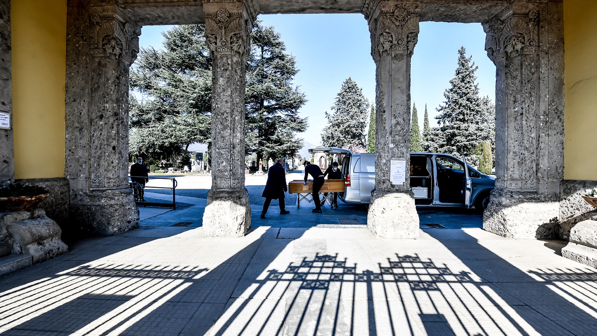 Undertakers carry a coffin out of a hearse at Bergamo's cemetery in northern Italy, March 16, 2020. 