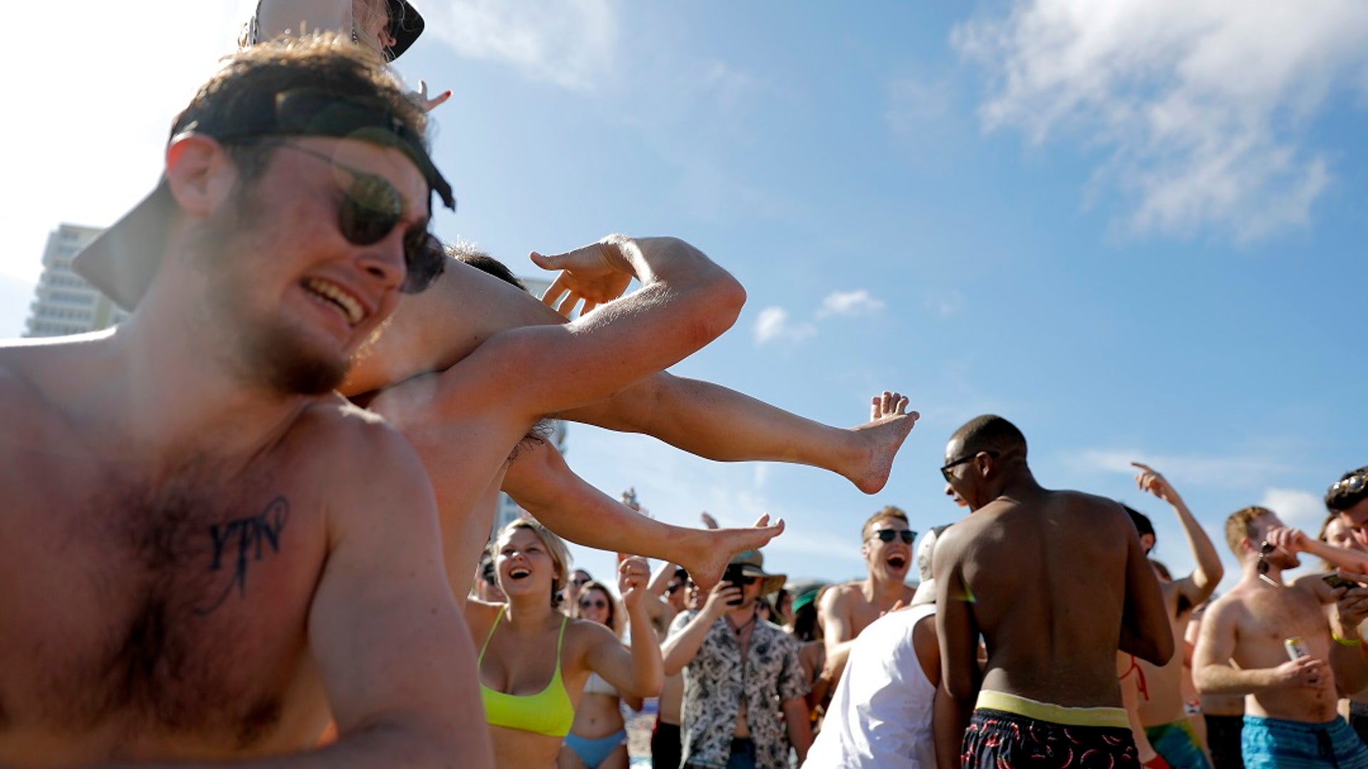 Spring break revelers party on the beach, Tuesday, March 17, 2020, in Pompano Beach, Florida. As a response to the coronavirus pandemic, Florida Gov. Ron DeSantis ordered all bars be shut down for 30 days beginning at 5 p.m. and many Florida beaches are turning away spring break crowds urging them to engage in social distancing. (AP Photo/Julio Cortez)