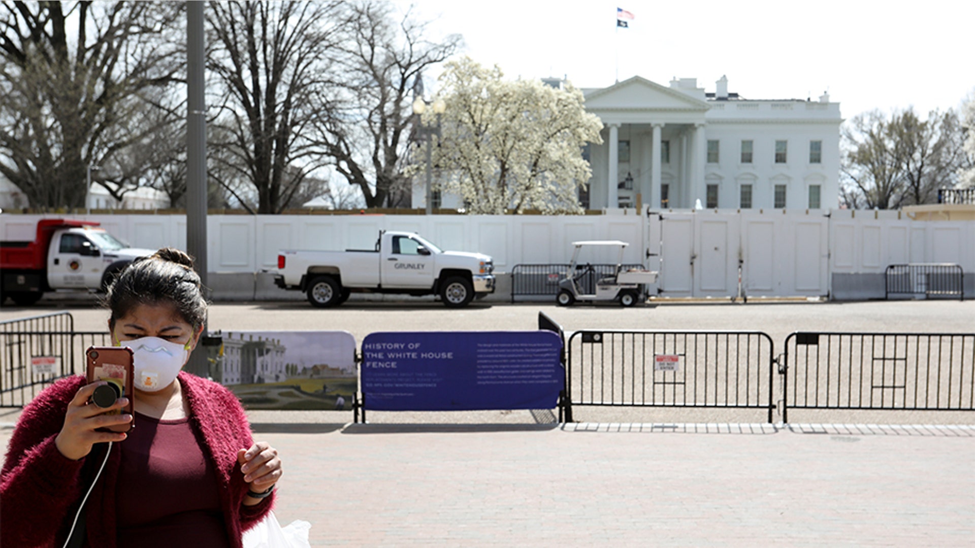 Washington, D.C.: A tourist wearing a face mask taking a picture standing on the empty pedestrian plaza outside the White House.