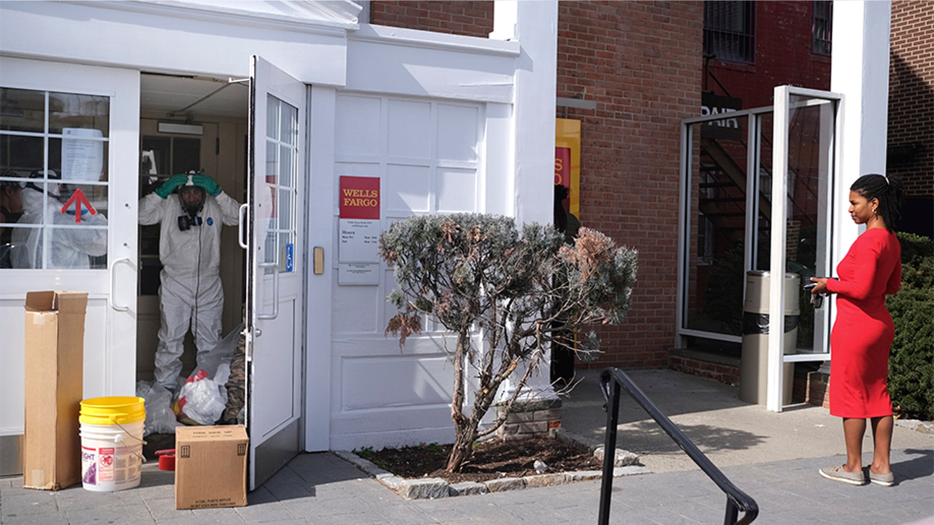 A woman waiting in line at an ATM watches as a cleaning crew worked in the bank in New Rochelle, N.Y.
