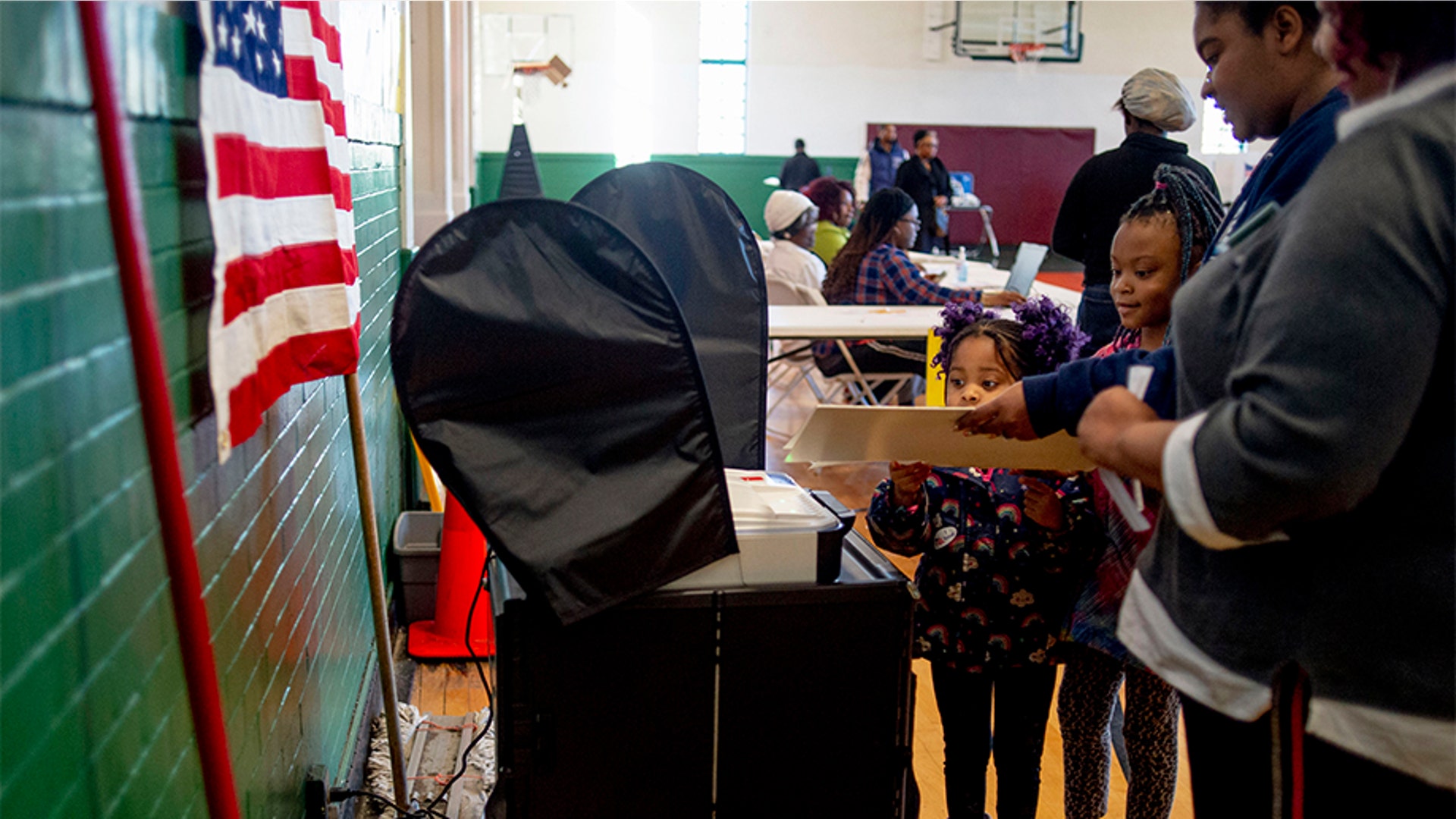 A pair of young girls helping their mother submit her ballot at Haskell Community Center in Flint, Michigan.