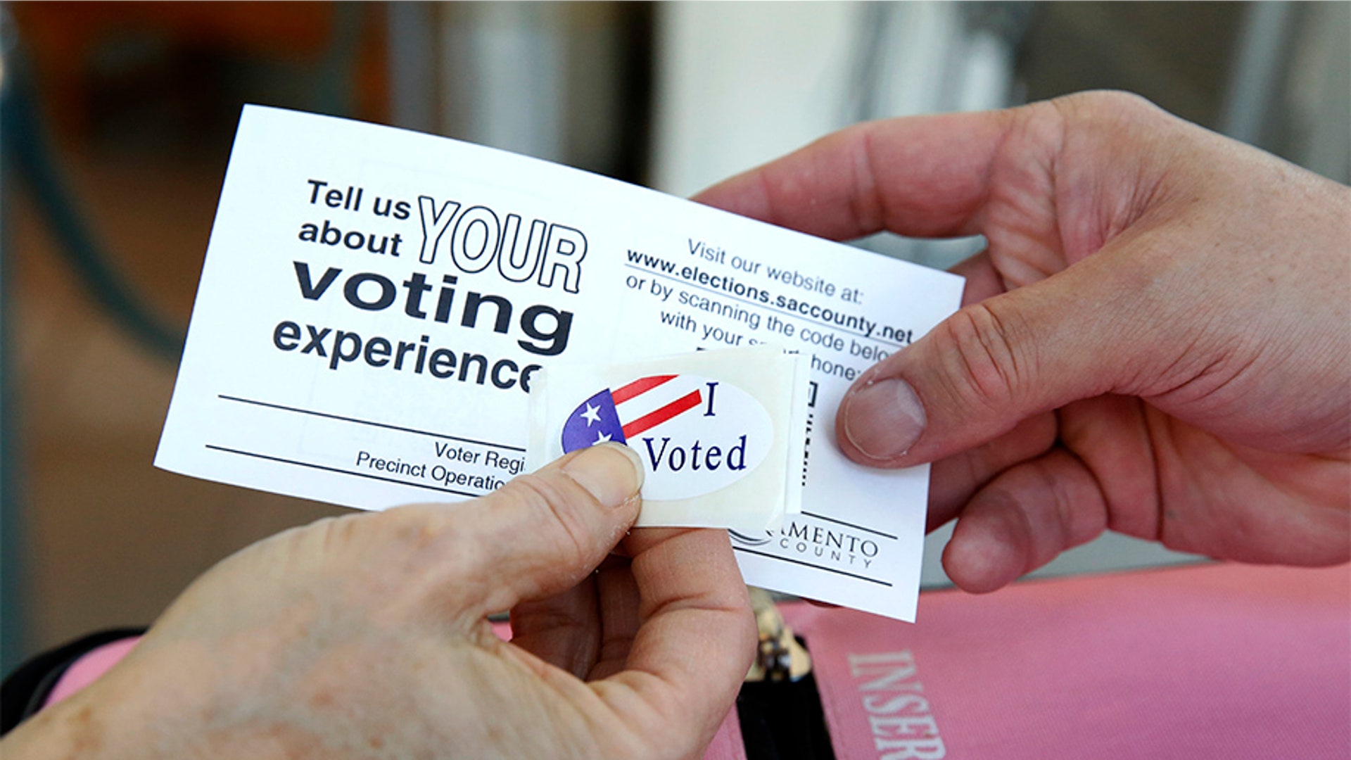 Chris Driller, left, is handed an "I Voted" sticker by vote center worker Edgar Sanchez after casting her ballot on the eve, at a voting center in Sacramento, Calif., Monday, March 2, 2020. Sacramento County is among the 15 counties in the state that have replaced traditional polling places with multi-purpose "vote centers" where people who live anywhere in the county can vote early, drop off ballots or register to vote.