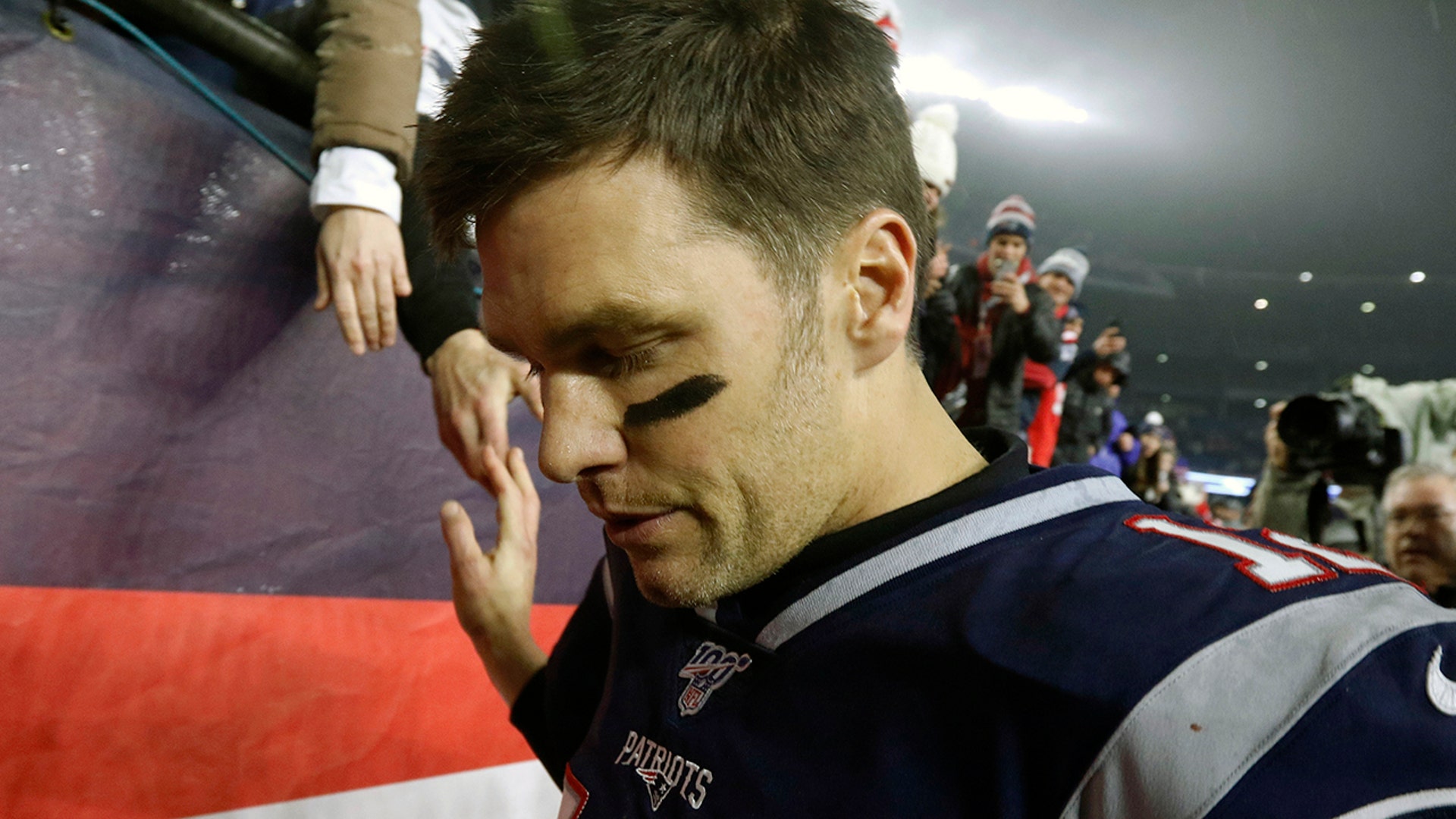 New England Patriots quarterback Tom Brady shakes hands with a fan as he leaves the field after losing an NFL wild-card playoff football game to the Tennessee Titans in Foxborough, Mass. 