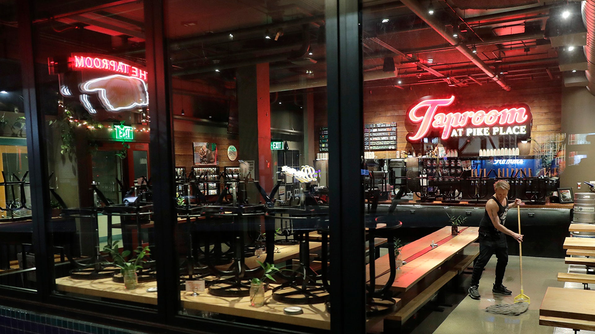 Tyler Baldwin mops the floor after closing for the night at the Taproom at Pike Place, Sunday, March 15, 2020 where he works as a bartender in Seattle. Washington Gov. Jay Inslee said Sunday night that he would order all bars, restaurants, entertainment and recreation facilities in the state to temporarily close to fight the spread of coronavirus, as Washington state has by far the most deaths in the U.S. from the disease. Baldwin said he closed more than an hour early Sunday after he heard the announcement.