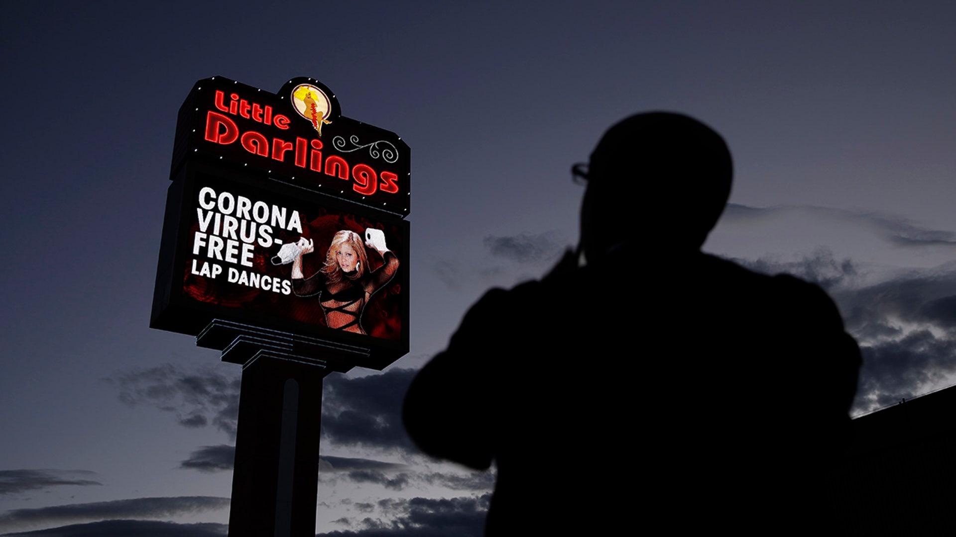 A man looks at a sign at a strip club advertising "coronavirus-free lap dances" Friday, March 13, 2020, in Las Vegas.