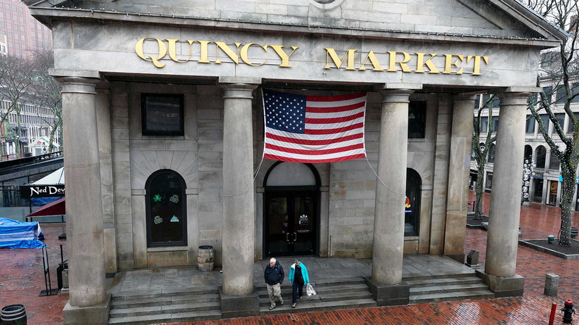 A couple walks onto a deserted plaza at the usually busy tourist site at Quincy Market in Boston, Friday, March, 13, 2020.