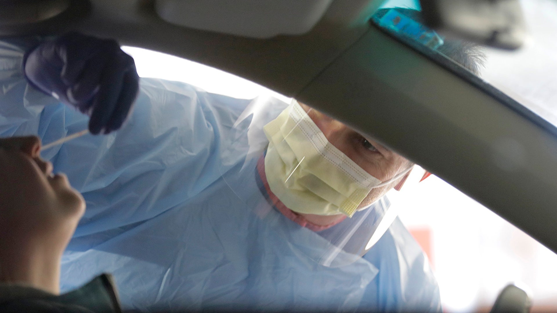 A nurse at a drive-up coronavirus testing station set up by the University of Washington Medical Center uses a swab to take a sample from the nose of a person in a car Friday, March 13, 2020, in Seattle. UW Medicine is conducting testing in a hospital parking garage and has screened hundreds of staff members, faculty and trainees for COVID-19. U.S. hospitals are setting up triage tents, calling doctors out of retirement, guarding their supplies of face masks and making plans to cancel elective surgery as they brace for an expected onslaught of coronavirus patients.