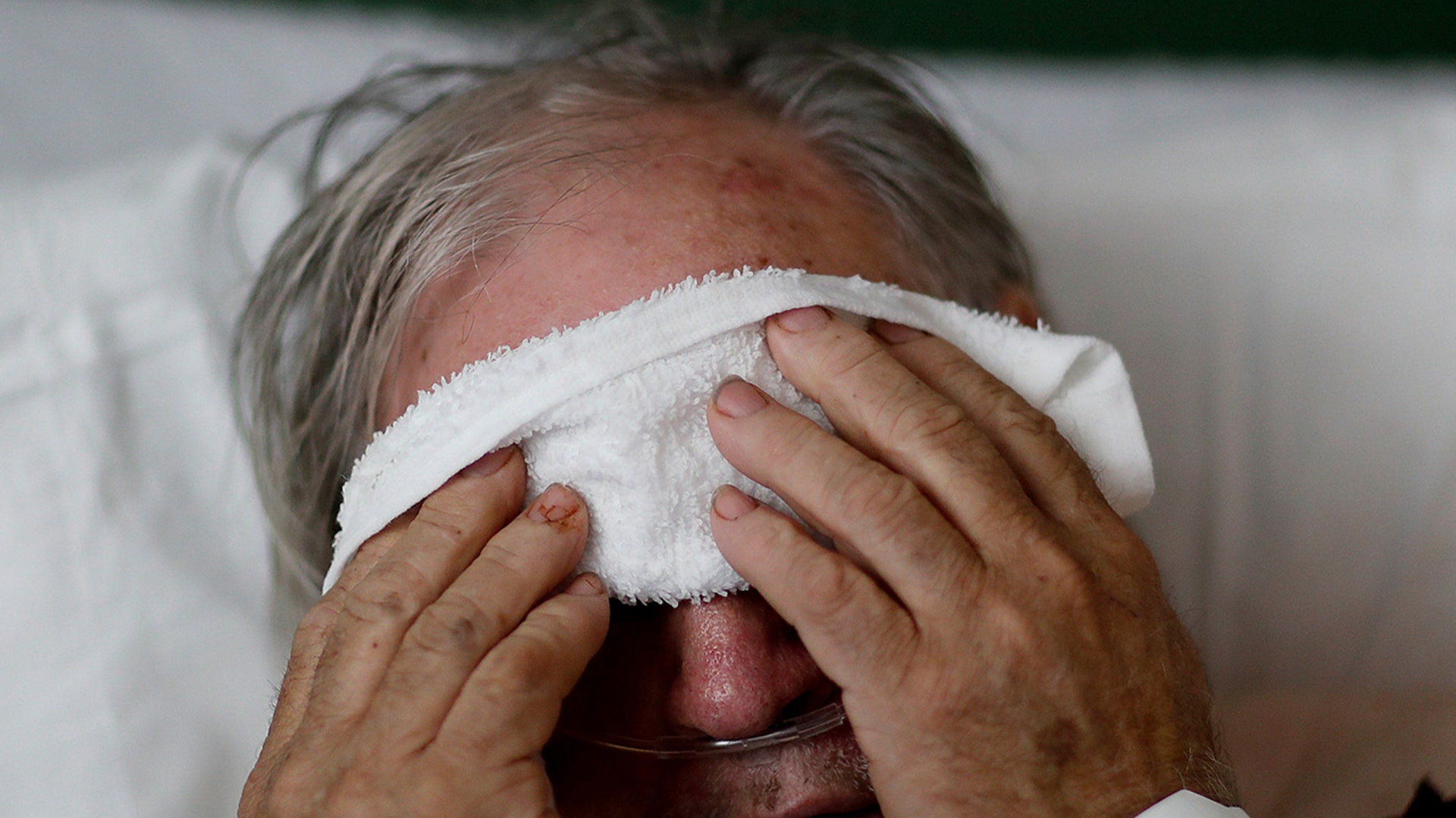 A 73-year-old man places a cold compress on his forehead while battling the flu at a hospital in Georgia. Doctors can test for the flu and get results within a day, but coronavirus testing as of March 2020 is still limited in the United States by availability.