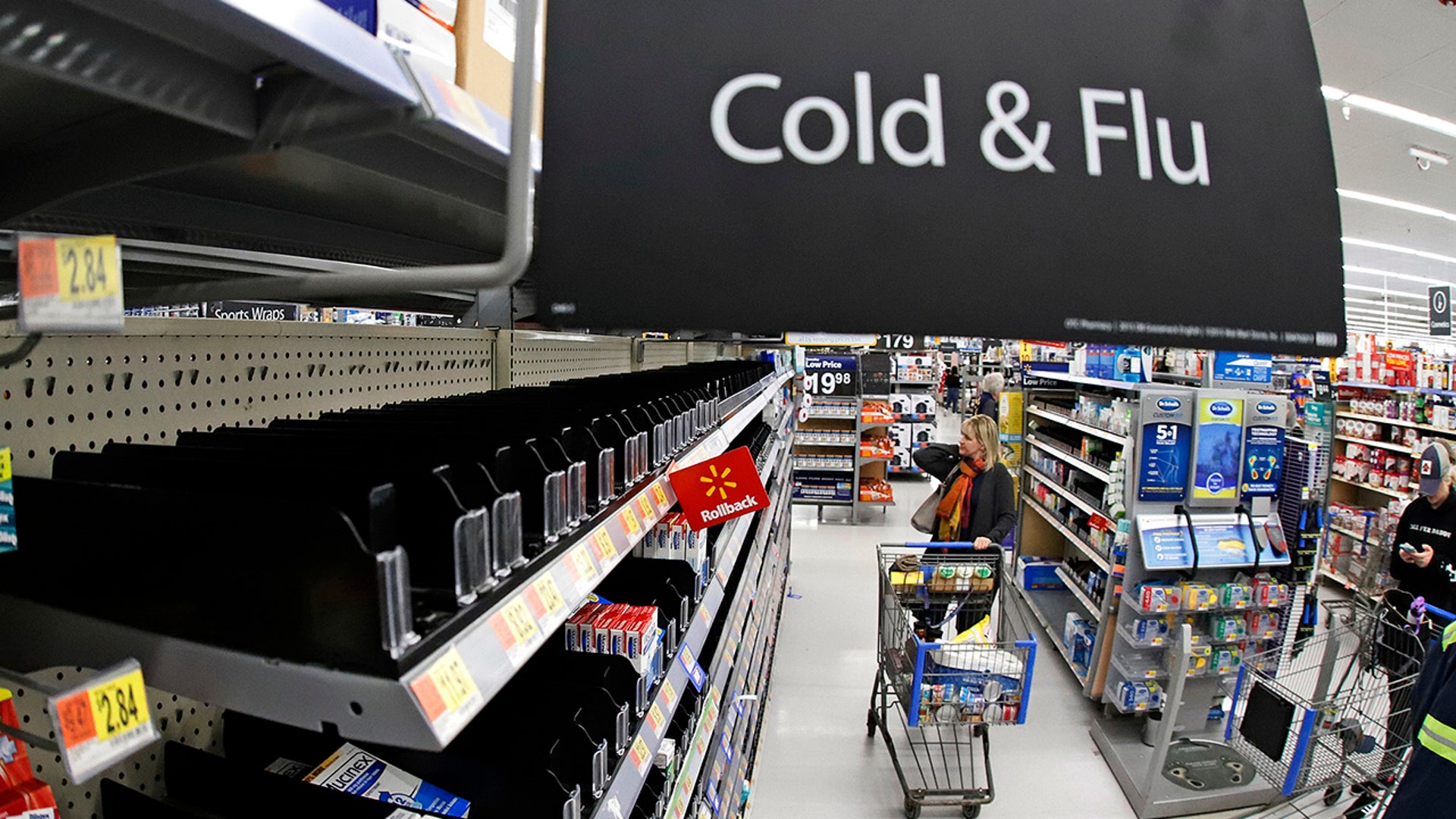 A woman looks at the few selections remaining in the cold and flu aisle of a Walmart near Warrendale, Pa. Walmart, the nation’s largest retailer and private employer, said late Saturday, March 14, 2020, it is limiting store hours to ensure they can keep sought-after items such as hand sanitizer in stock amid the coronavirus pandemic.