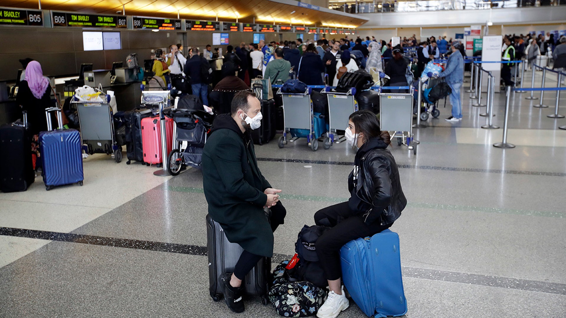 Travelers wait to check in their luggage at the Los Angeles International Airport Saturday, March 14, 2020, in Los Angeles. The coronavirus outbreak is hitting the airline industry hard. President Trump banned most Europeans from entering the United States for 30 days to try to slow down the spread of the virus. The new travel ban is likely to further roil the airline industry as bookings decline and people cancel reservations out of fear they might contract the virus.