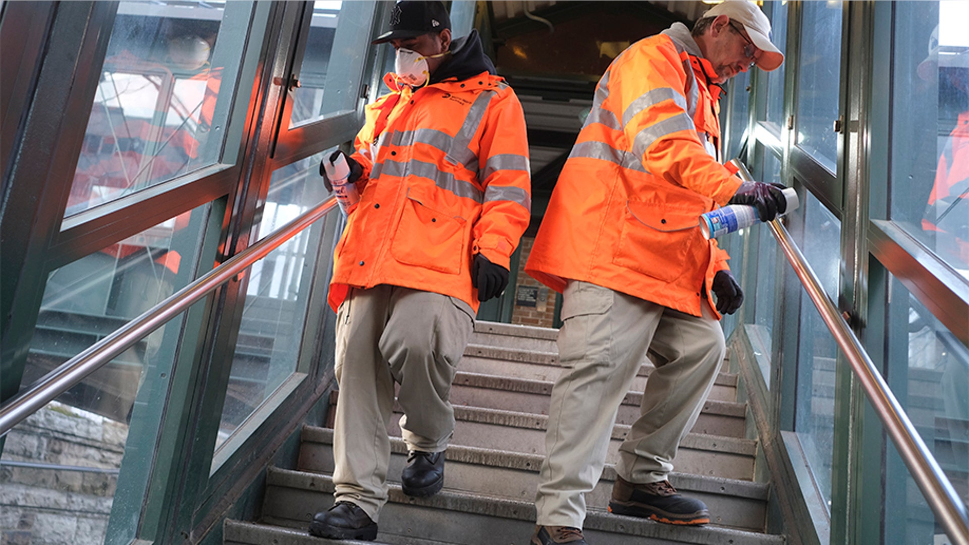 Employees of Metro-North Railroad disinfecting handrails at the New Rochelle Metro-North station.