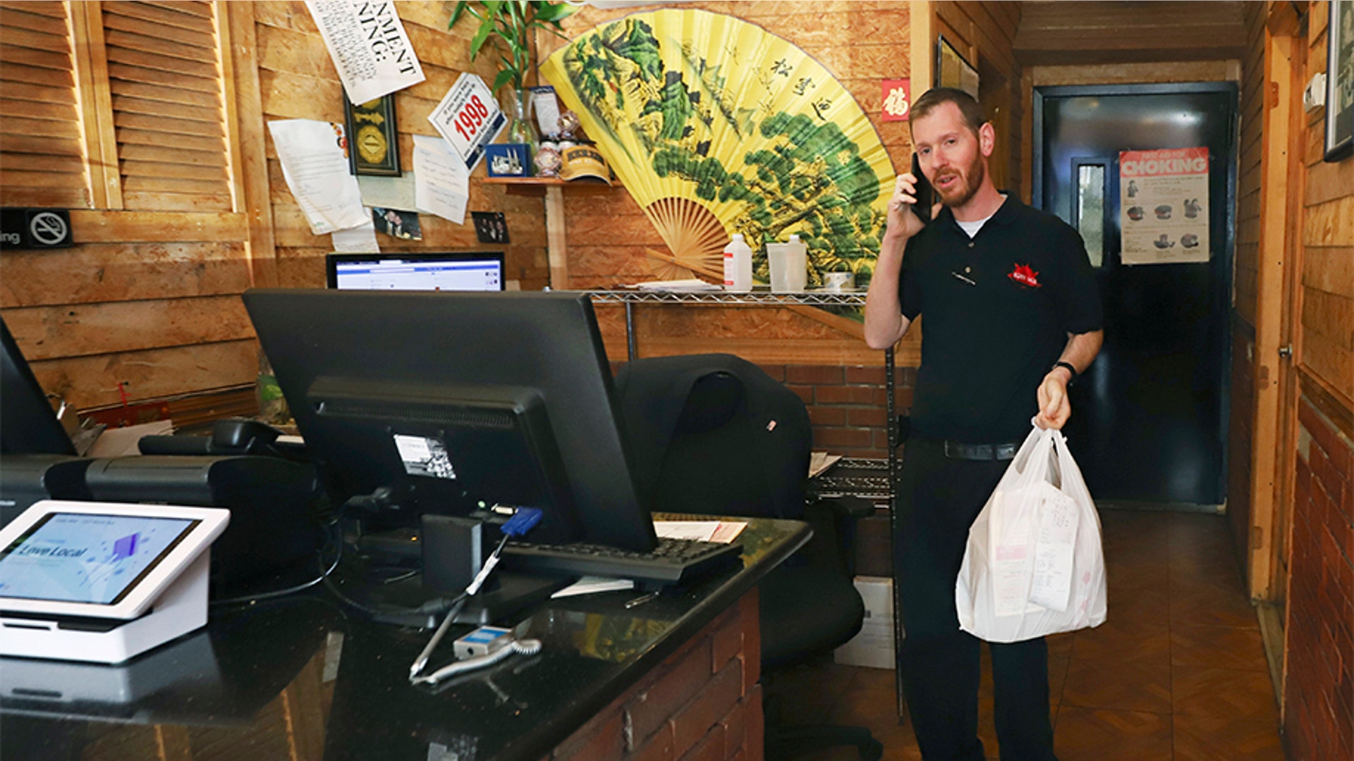 Restaurant owner Joshua Berkowitz talking on the phone at Eden Wok, prior to going out on a delivery. Berkowitz, whose restaurant is located inside a containment area, said customers have been grateful for deliveries.
