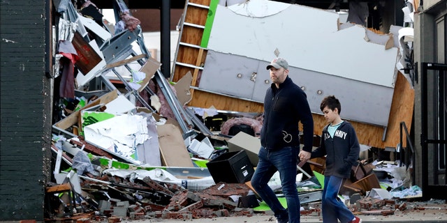 People walk past buildings damaged by storms Tuesday, March 3, 2020, in Nashville, Tenn.