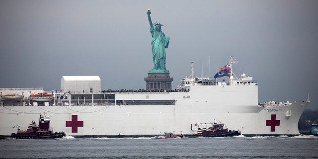 The U.S. Navy hospital ship "Comfort" passes in front of the Statue of Liberty as it arrives in New York, U.S., on Monday, March 30, 2020. The naval hospital has 1,000 beds and 12 operating rooms. The Comfort will not treat Covid-19 patients, but rather handle overflow or acute trauma cases and other urgent needs, Acting Navy Secretary Thomas Modly told reporters at a briefing last week. Photographer: Michael Nagle/Bloomberg via Getty Images