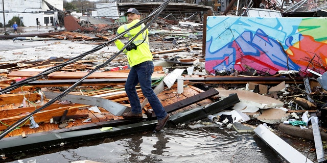 A man makes his way through debris following a deadly tornado Tuesday, March 3, 2020, in Nashville, Tenn.