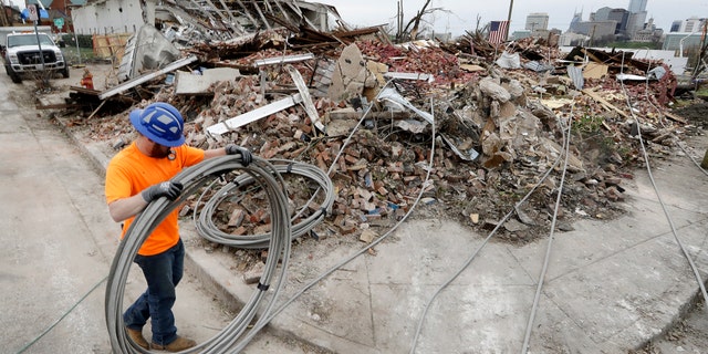 Electrical worker Tyler Morris rolls up damaged power cable Wednesday, March 4 near a store destroyed by a storm in Nashville, Tenn.