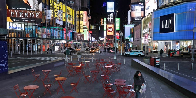 A woman walks through a lightly trafficked Times Square in New York, Monday, March 16, 2020. (AP Photo/Seth Wenig)