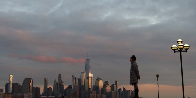 HOBOKEN, NJ - MARCH 17: A woman watches from Pier A as the sun sets in New York City on March 17, 2020 in Hoboken, New Jersey. The municipal government in Hoboken issued a self-isolation policy to fight the community spread of the coronavirus today.(Photo by Gary Hershorn/Getty Images)
