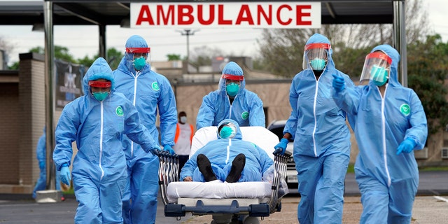 A person is taken on a stretcher into the United Memorial Medical Center after going through testing for COVID-19 Thursday, March 19, 2020, in Houston. People were lined up in their cars in a line that stretched over two miles to be tested in the drive-thru testing for coronavirus. (AP Photo/David J. Phillip)