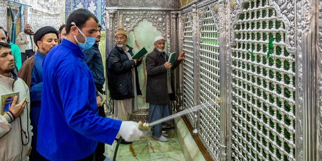 In this Monday, Feb. 24, 2020, photo, a man disinfects the shrine of Saint Masoumeh against coronavirus in the city of Qom 78 miles south of the capital Tehran, Iran. (Ahmad Zohrabi/ISNA via AP)