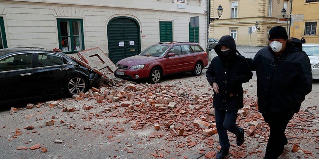 People walk past a damaged house after an earthquake in Zagreb, Croatia, Sunday, March 22, 2020. A strong earthquake shook Croatia and its capital on Sunday, causing widespread damage and panic.(Associated Press)