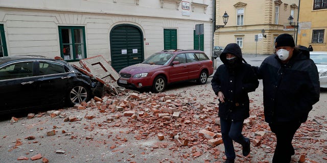 People walk past a damaged house after an earthquake in Zagreb, Croatia, Sunday, March 22, 2020. A strong earthquake shook Croatia and its capital on Sunday, causing widespread damage and panic.(Associated Press)