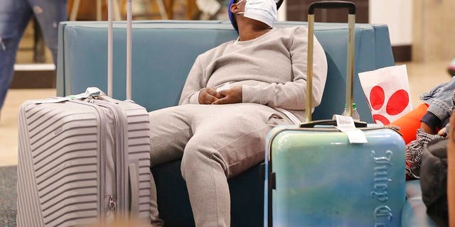 An airline passenger wears a mask in the terminal area of Orlando International Airport on Wednesday, March 4, 2020, in Orlando, Fla. Many travelers are wearing masks because of the coronavirus outbreak.