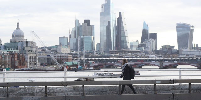 A commuter crosses an empty Waterloo Bridge in London on Tuesday after British authorities ramped up public health measures, telling people who are in the groups considered most vulnerable to severe COVID-19 illness to stay at home for three months. (Jonathan Brady/PA via AP)