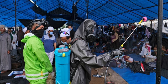 Paramilitary police officers in hazmat suit disinfect a tent built on a field where a mass congregation was supposed to be held in Gowa, South Sulawesi, Indonesia, on Thursday. (AP)