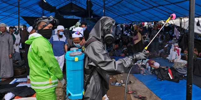 Paramilitary police officers in hazmat suit disinfect a tent built on a field where a mass congregation was supposed to be held in Gowa, South Sulawesi, Indonesia, on Thursday. (AP)