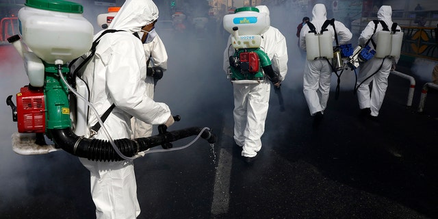 Firefighters disinfect a street against the new coronavirus in western Tehran on Friday as the virus continues to spread throughout the nation. (AP Photo/Vahid Salemi)